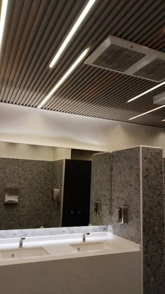 Renovated washroom with a dark slatted ceiling and linear lighting at Barry Callebaut, Pasir Gudang