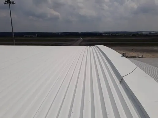 Completed white waterproof coating across the Senai Airport cargo warehouse roof, overlooking the apron